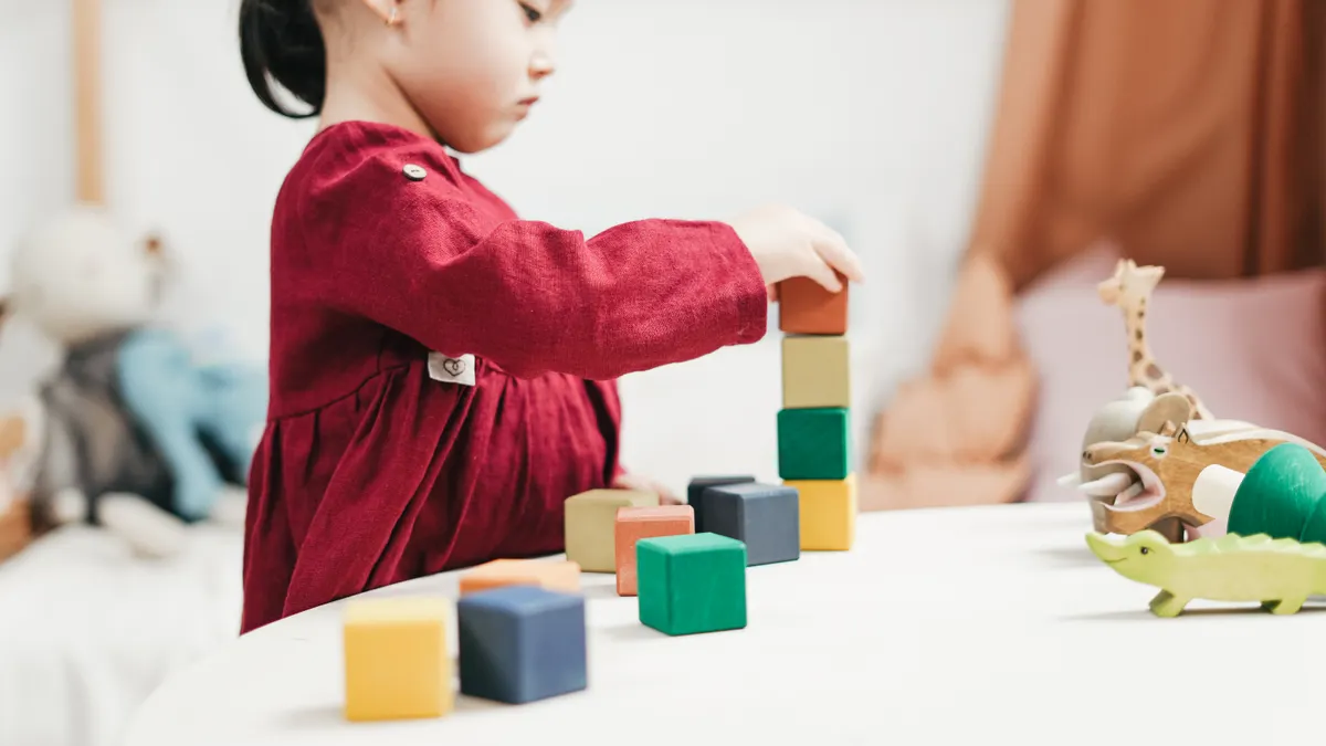 Child stacking colorful wooden blocks at a table