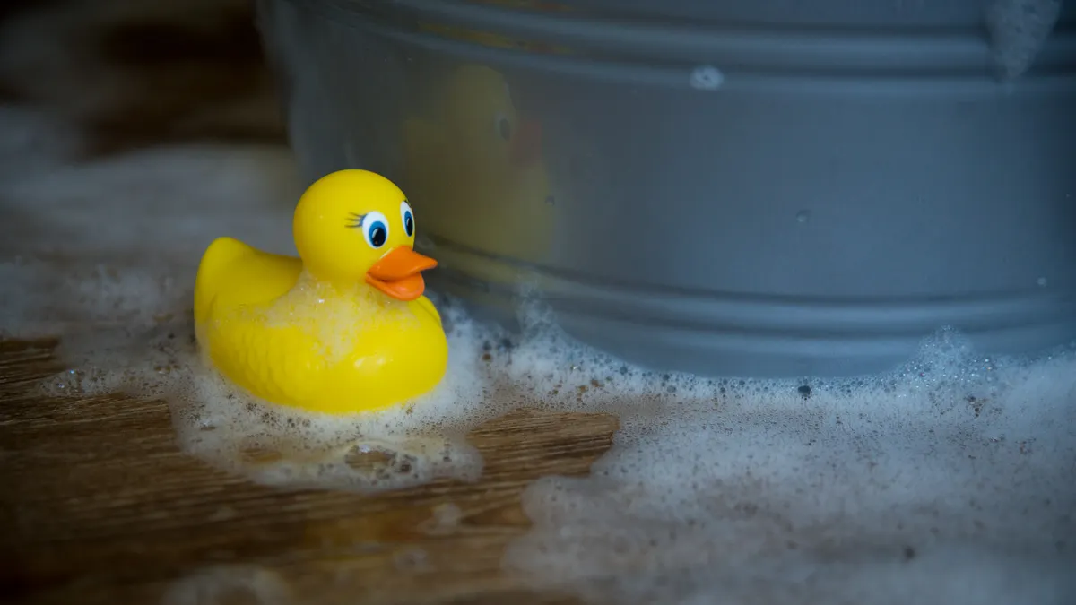 How to Clean and Sanitize Toddler Toys Without Damaging Them Rubber duck in suds beside a bucket