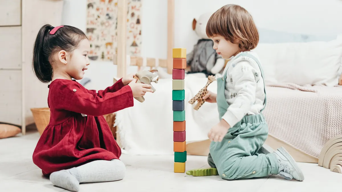 Safe toddler play — The Complete Guide Two toddlers playing with a stacker in a bright room